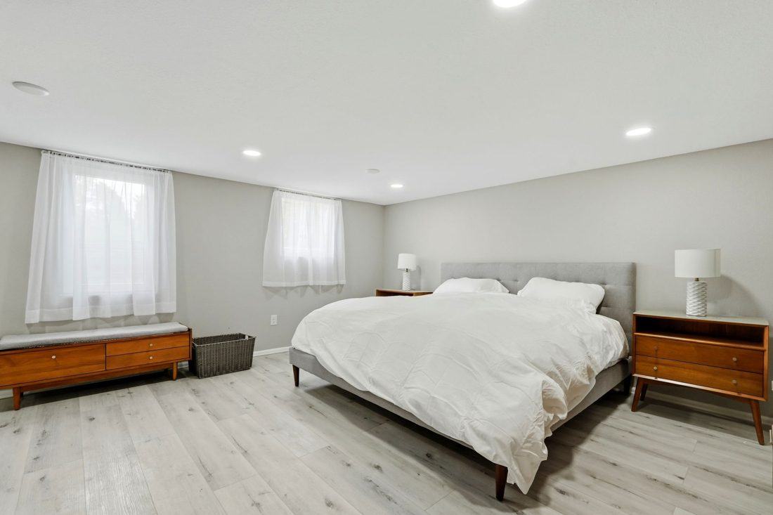 Seijaku: bed with white duvet, sheer curtains and wood-look floors